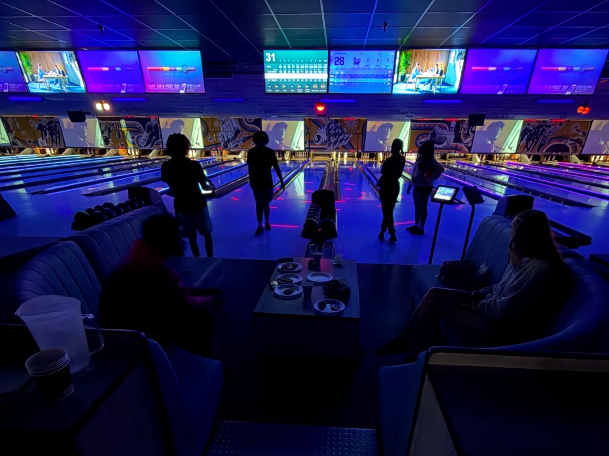 Teens bowling under black lights